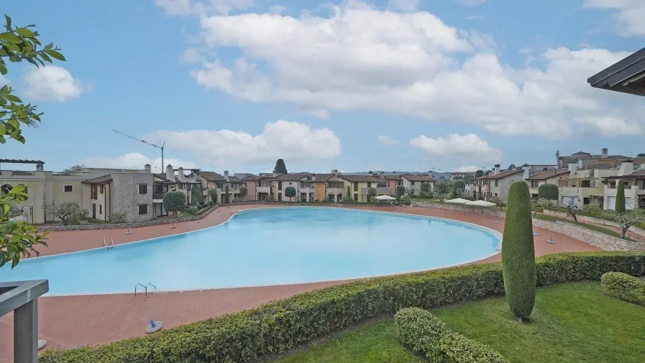 Piscina grande in residence con siepi e prato curato