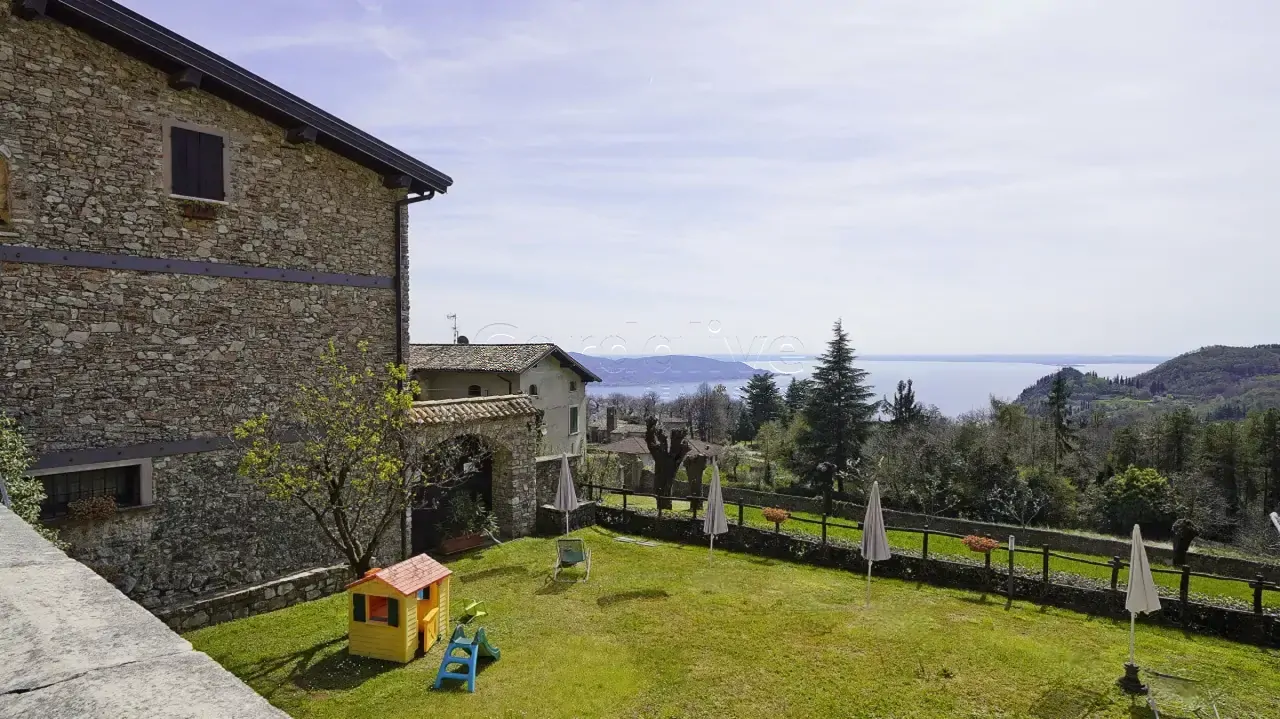 Giardino con sedie a sdraio, ombrelloni e casetta per bambini