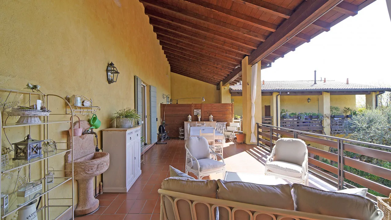 Überdachte Terrasse mit Gartenmöbeln und Metallgeländer