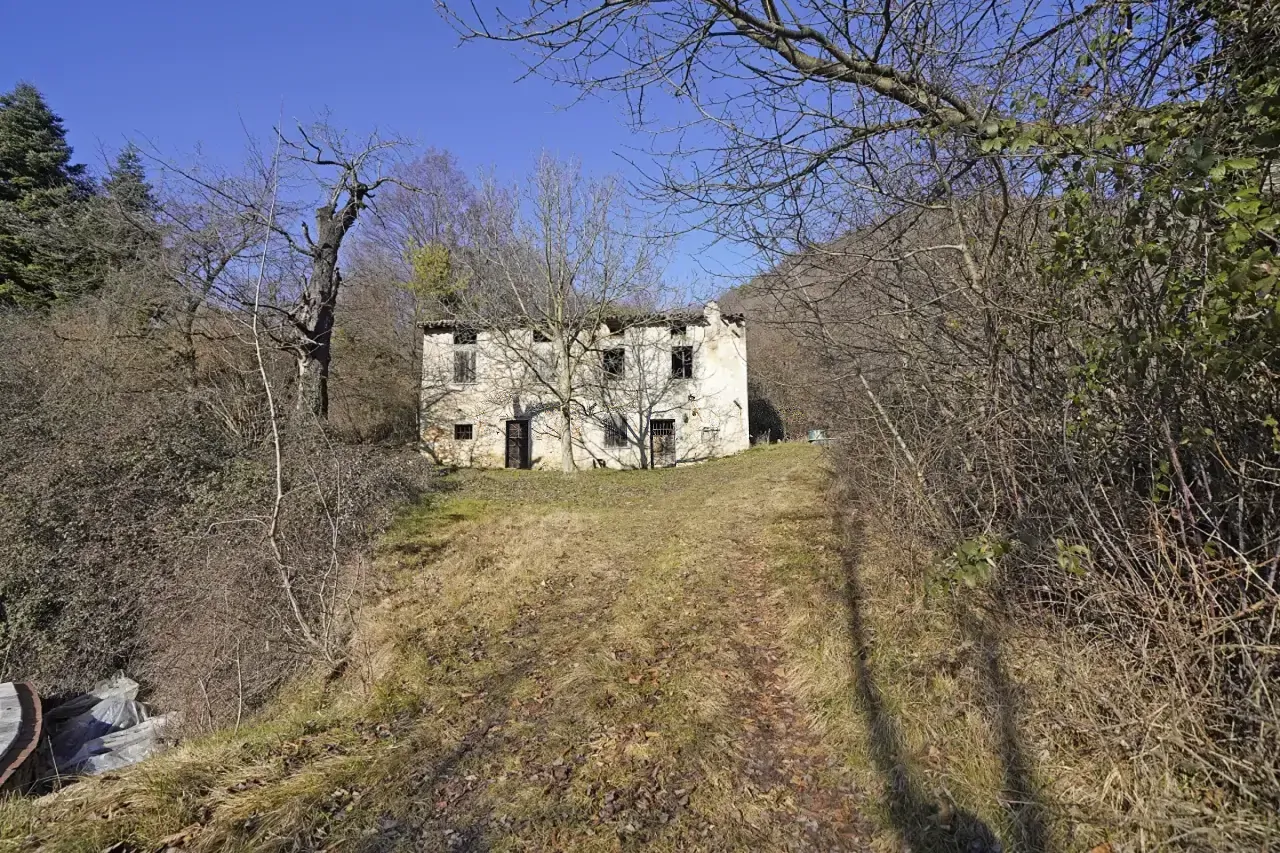 Rustico in pietra immerso nel verde con prato e alberi