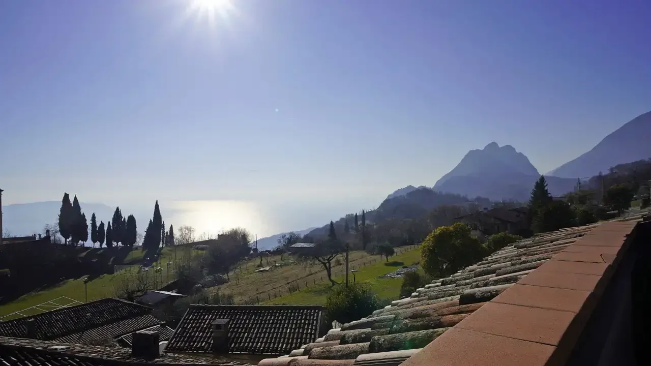 Panoramic view of lake and mountains with roofs in foreground