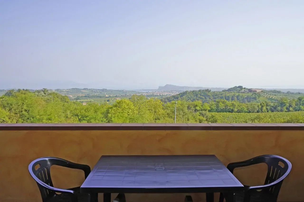 Terrazza con tavolo e sedie di plastica e vista panoramica sulle colline verdi