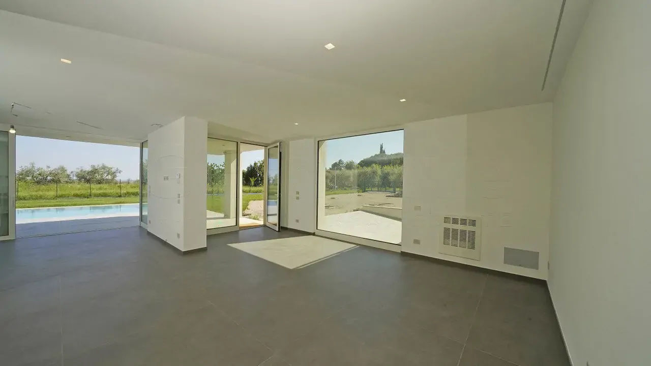 Wohnzimmer mit großen Fenstern und Blick auf Pool und Garten