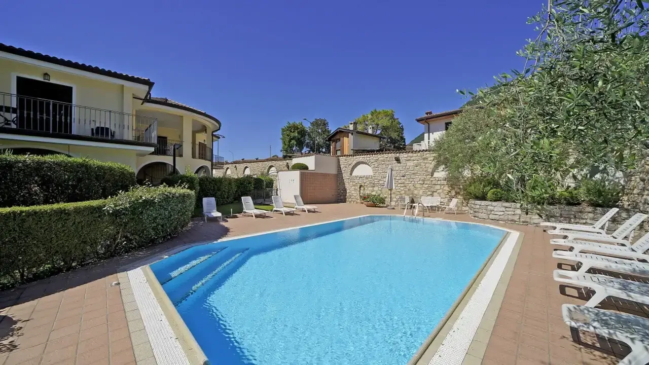 Piscina esterna con sdraio e muro in pietra