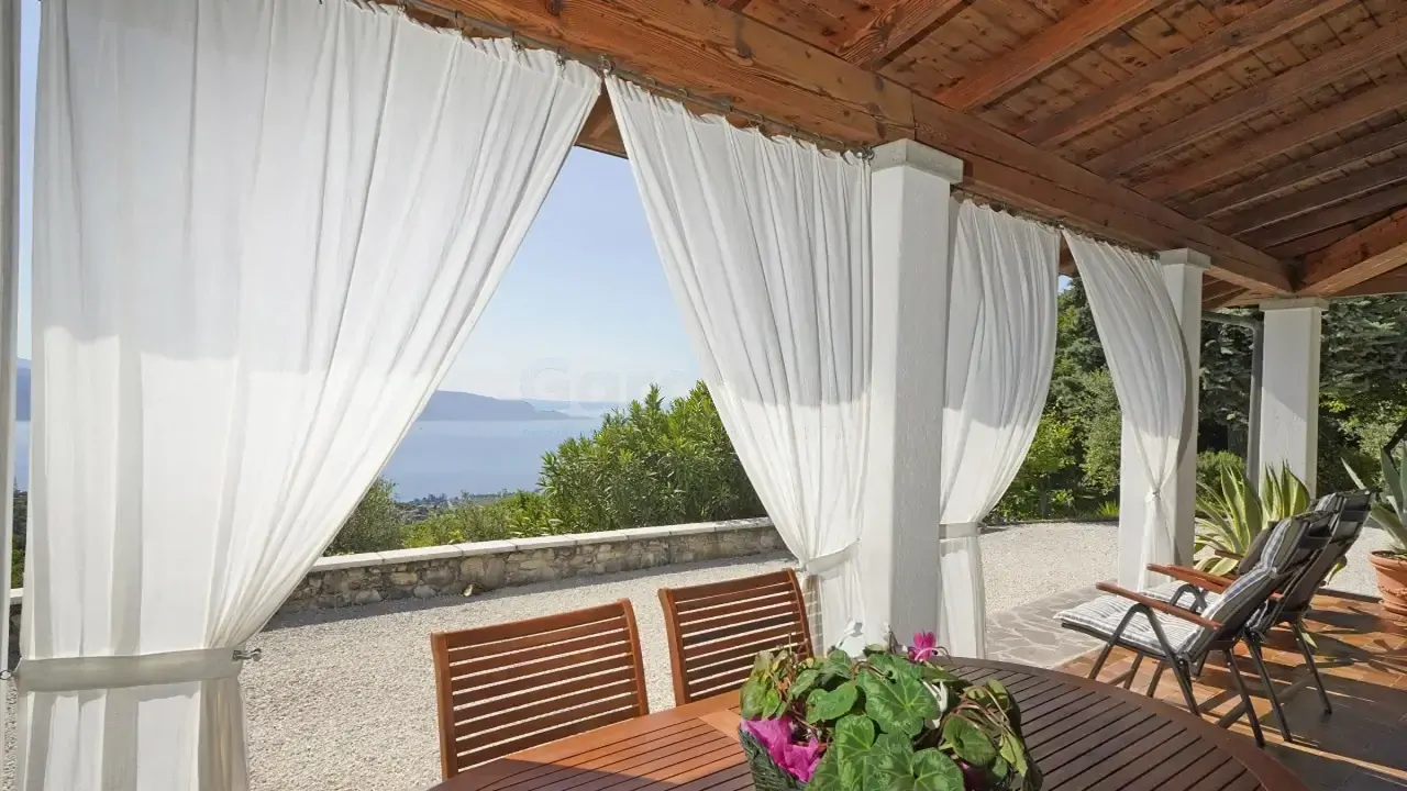 Überdachte Terrasse mit weißen Vorhängen und Seeblick