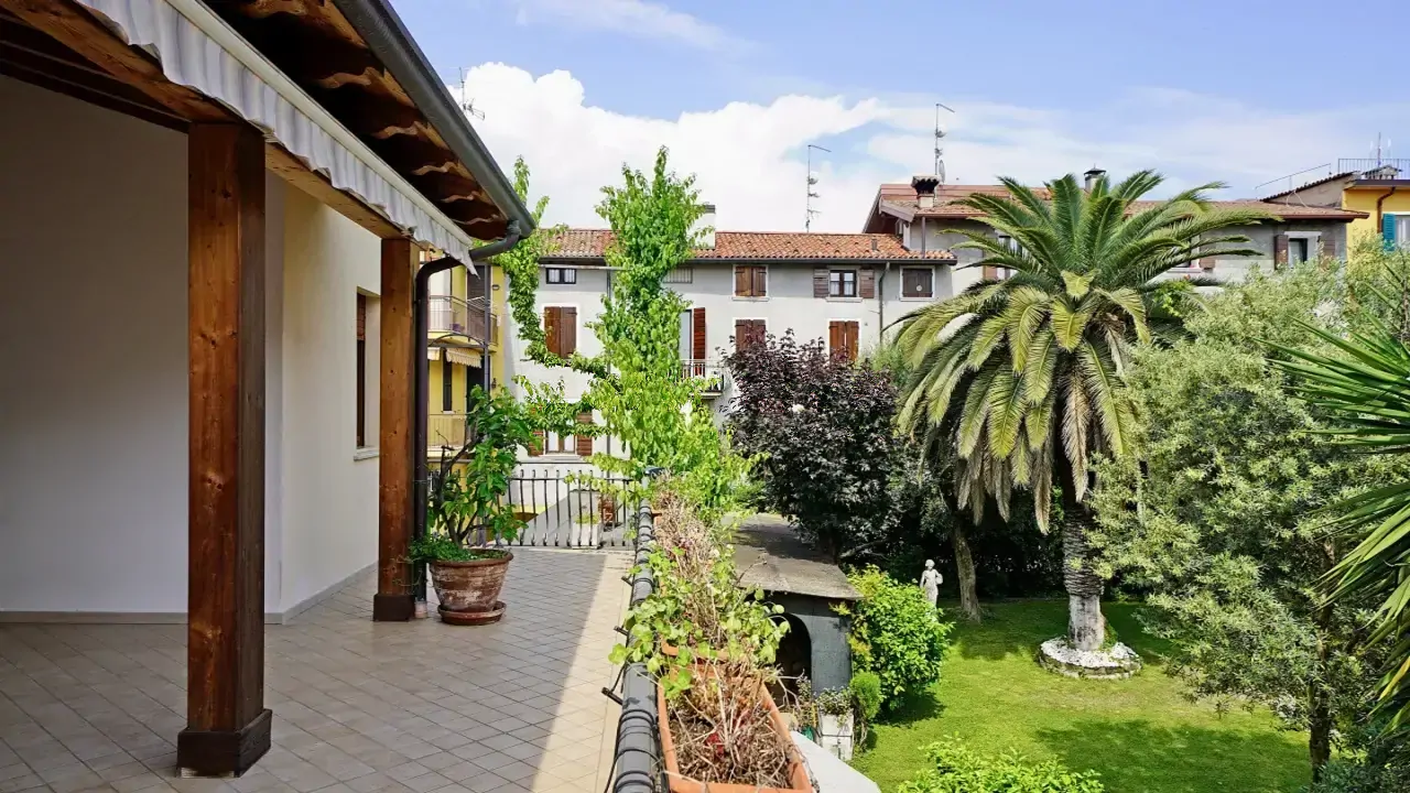 Terrace with railing overlooking private garden with palm tree and plants