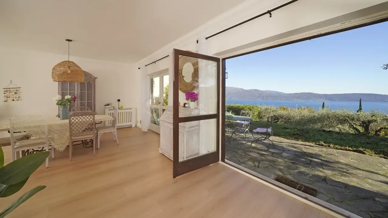 Wohnzimmer mit offener Terrassentür zum Garten und Seeblick