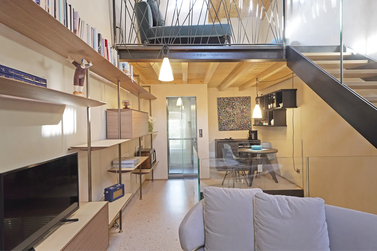 Living room with sofa, bookshelf, and internal metal and wood staircase