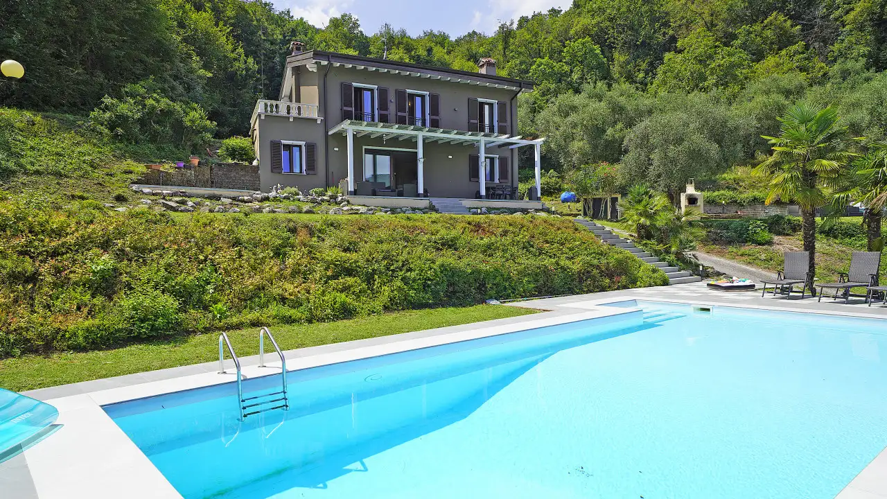Schwimmbad mit Villa und Garten im Hintergrund