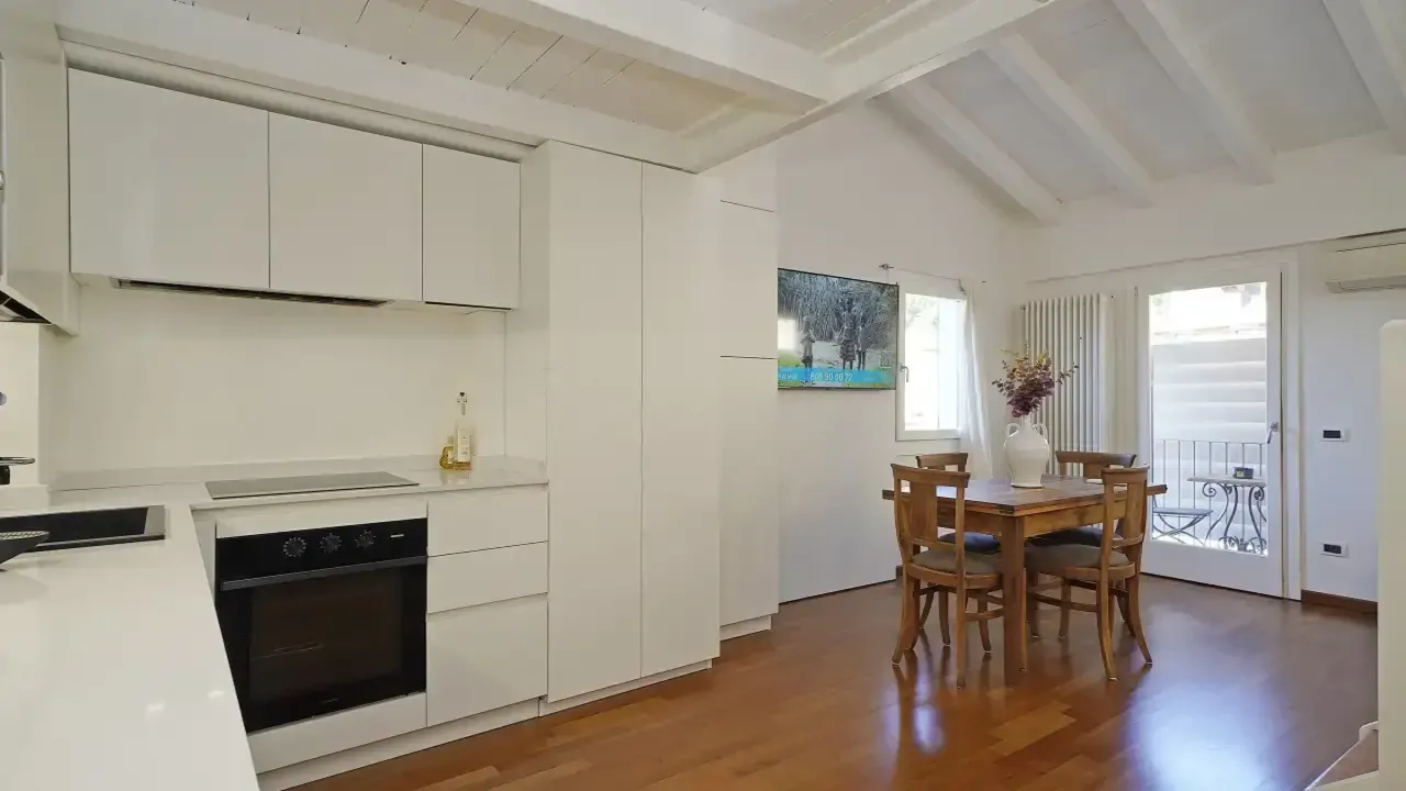 Cucina con mobili bianchi e tavolo in legno con quattro sedie