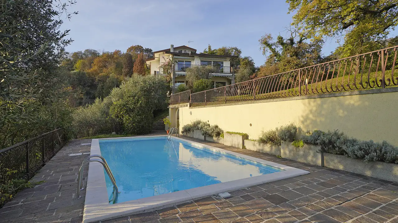 Rechteckiger Pool mit Steinrand und Mauer mit Eisenzaun