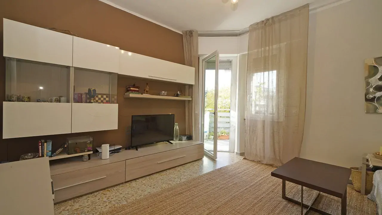 Wohnzimmer mit TV-Möbel und offener Tür zur Terrasse