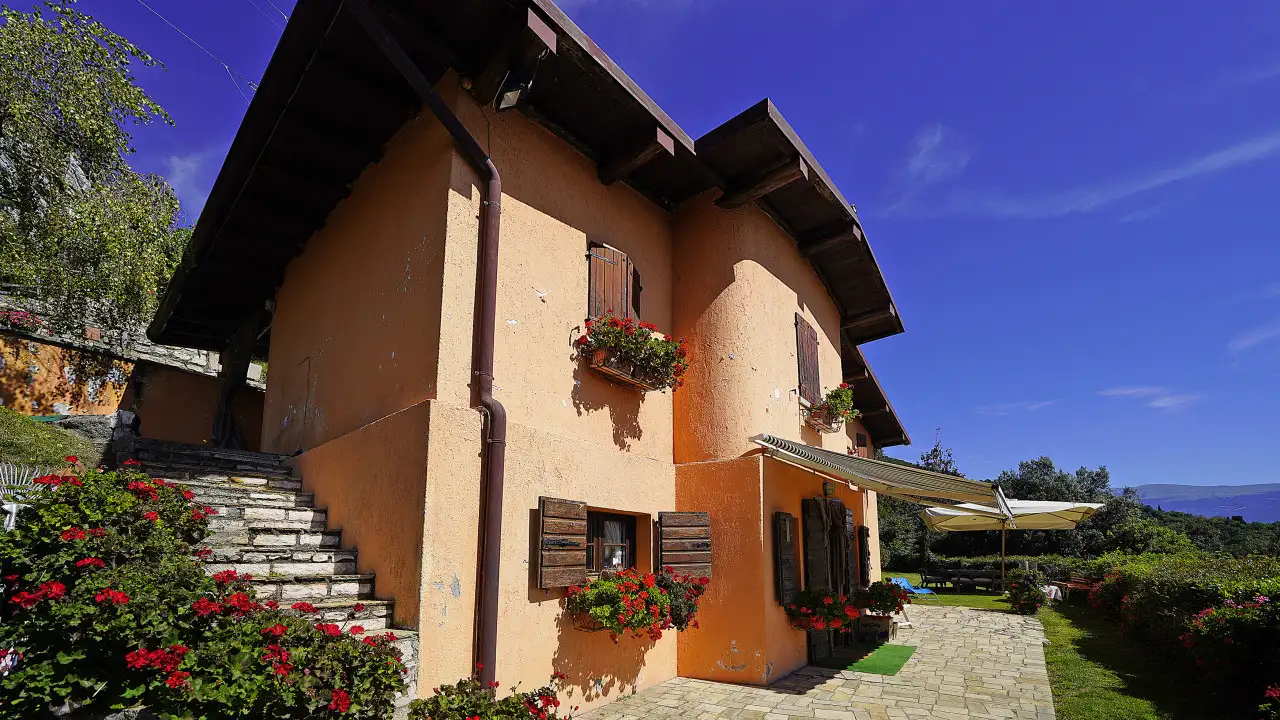 Hausfassade mit Blumen an den Fenstern und klarem Himmel
