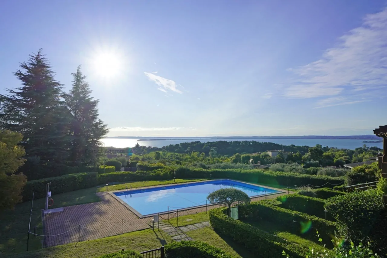 Piscina all'aperto con vista sul lago e cielo sereno