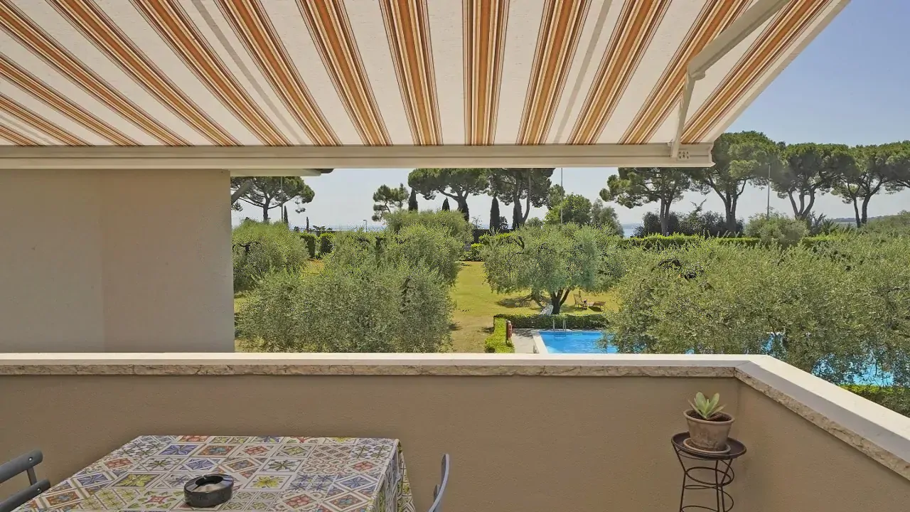 Terrazza con tenda e vista su giardino e piscina