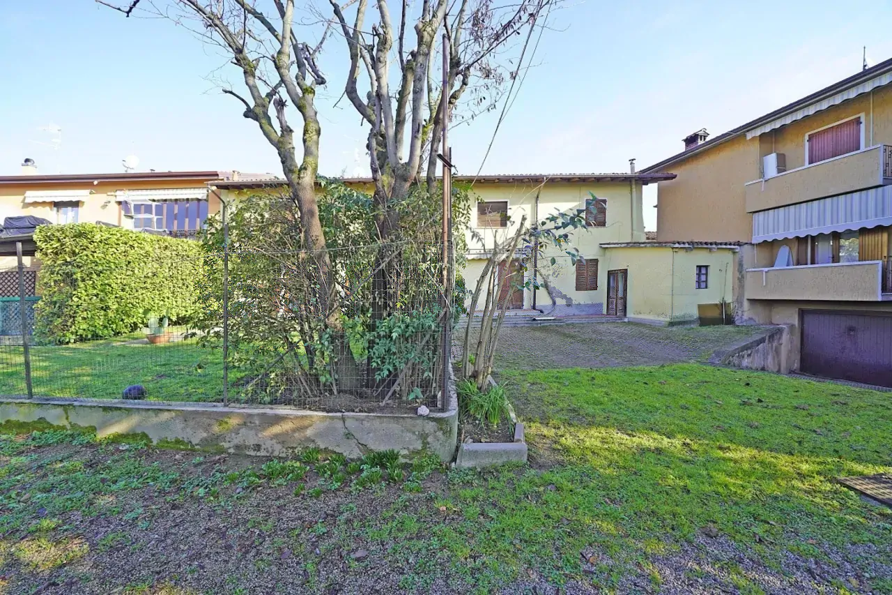 Garden with lawn and trees in front of yellow rustic house