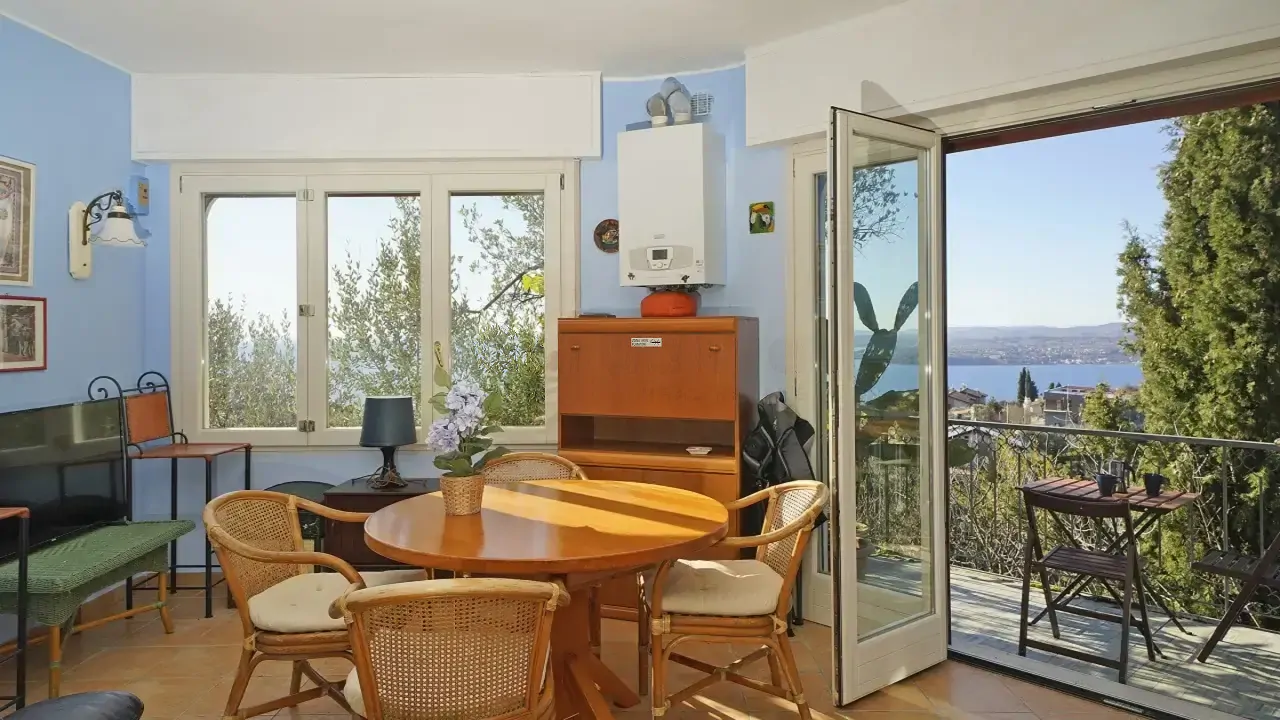 Wohnzimmer mit rundem Tisch und offener Tür zur Terrasse mit Seeblick