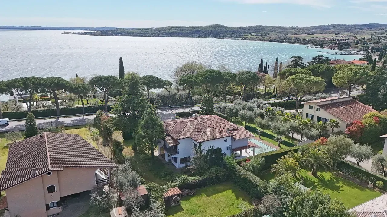 Aerial view of houses with gardens and lake in the background in Padenghe sul Garda