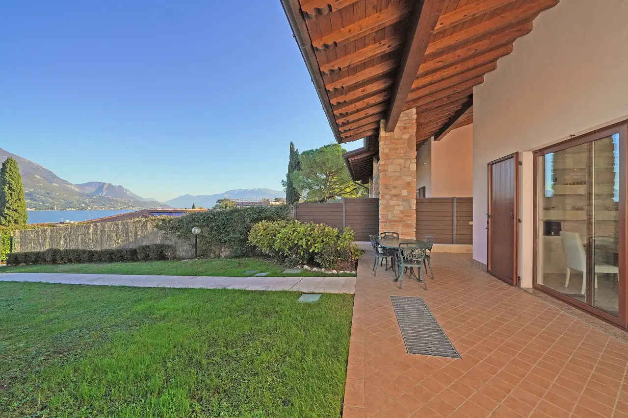 Portico con tavolo e sedie e vista sul giardino e sul lago
