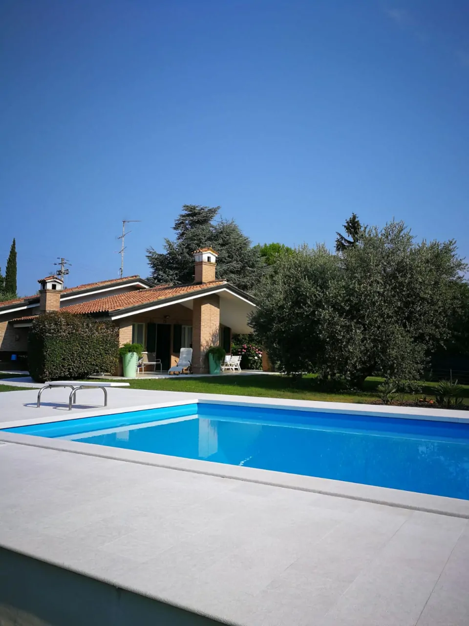 Piscina rettangolare con bordo in pietra e villa sullo sfondo
