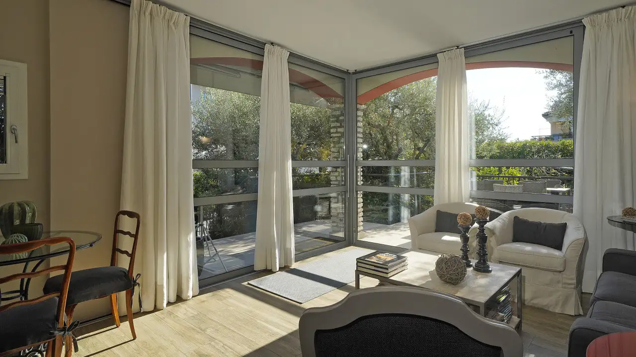 Living room with large corner windows and white curtains
