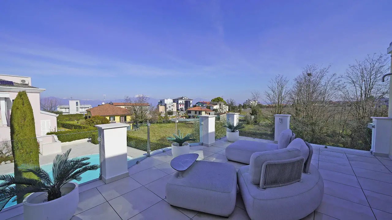 Terrace with sofa and table overlooking garden and pool