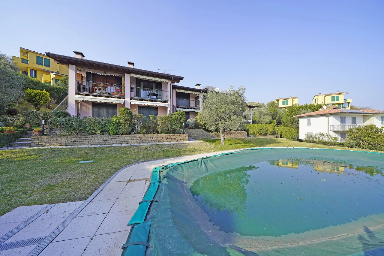 Covered pool with lawn and houses in the background