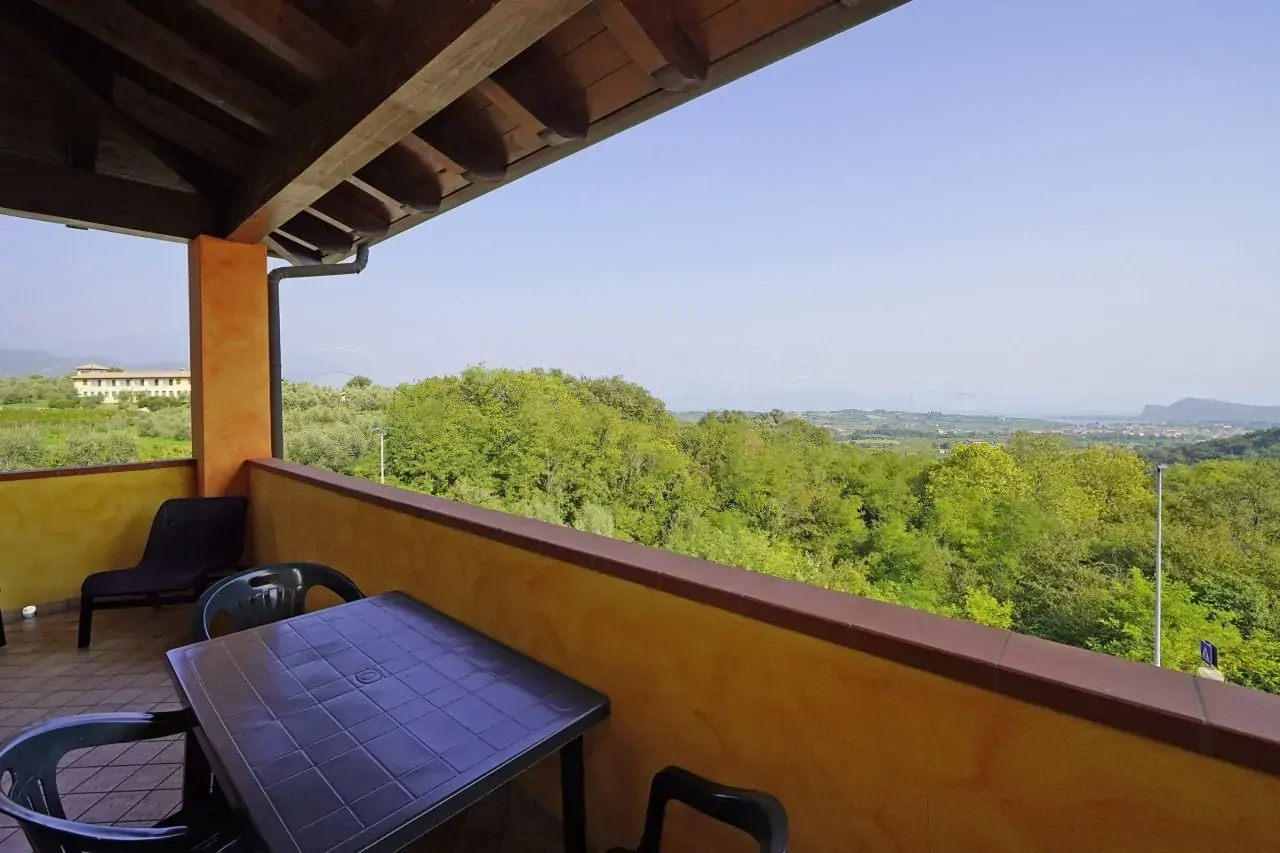 Terrazza con tavolo e sedie e vista su vegetazione e lago