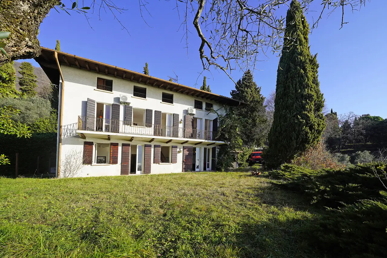 Facciata di villa con giardino e alberi in primo piano