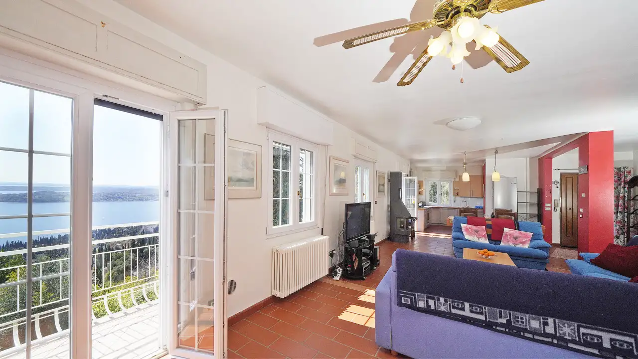 Wohnzimmer mit Sofas und offener Terrassentür mit Seeblick