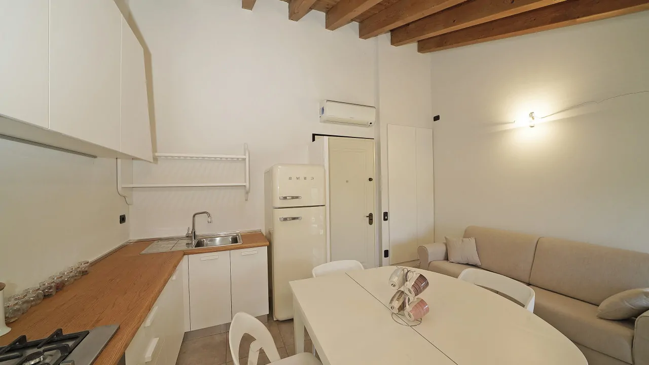 Soggiorno con cucina a vista e divano beige