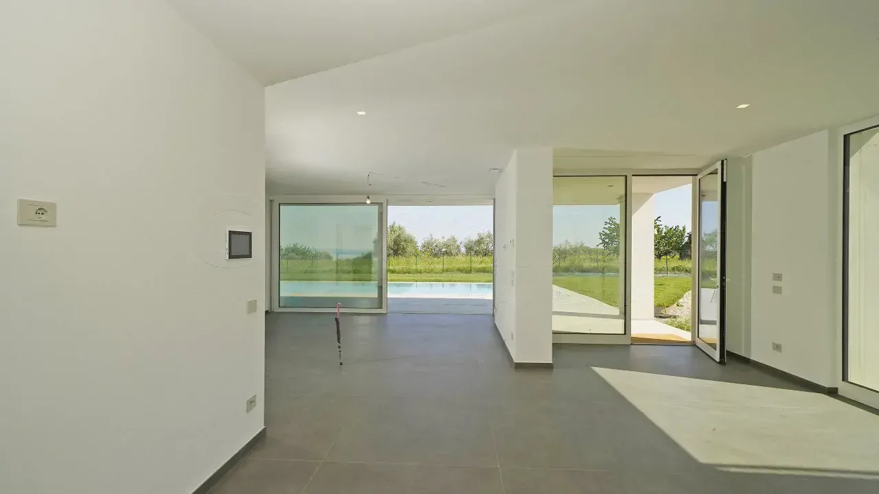 Wohnzimmer mit großen Fenstern mit Blick auf den Pool und Garten