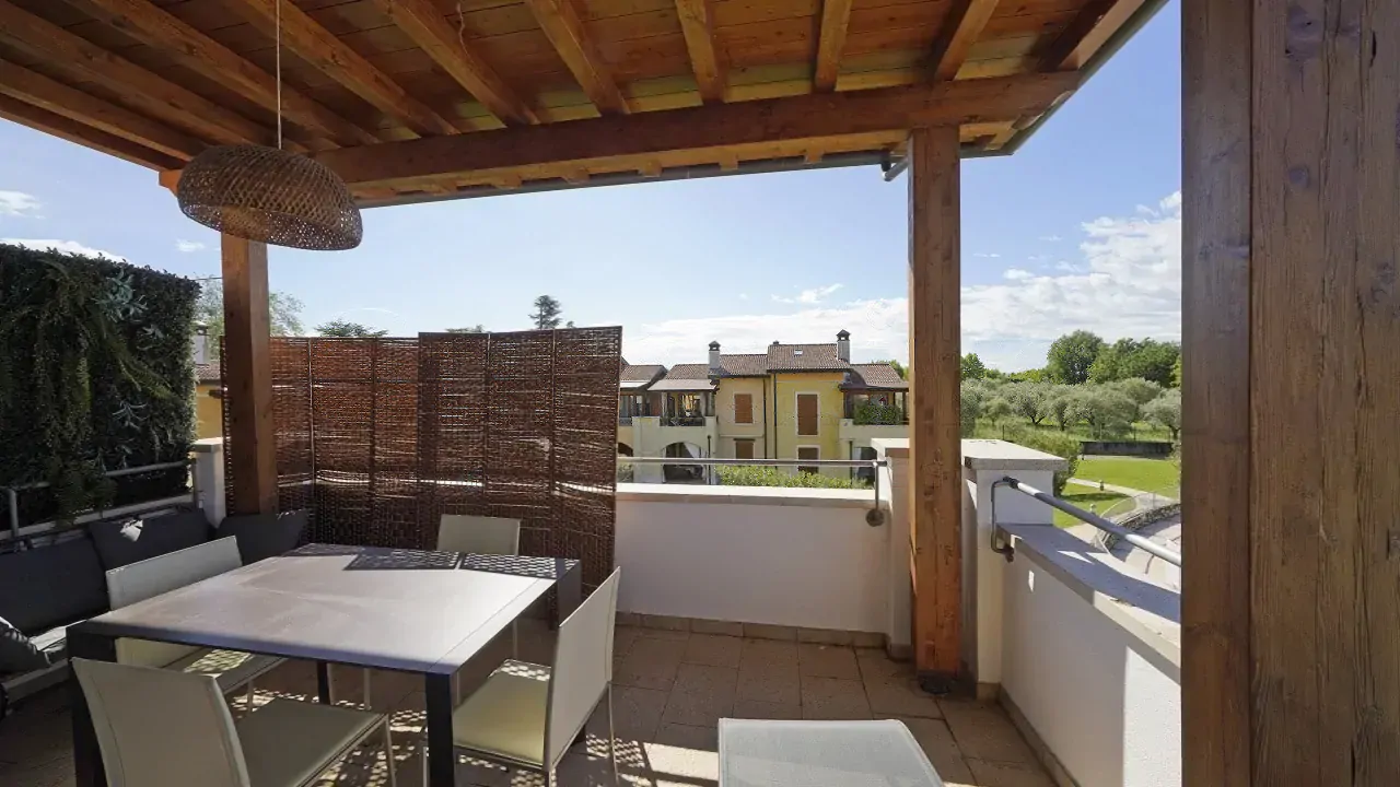 Überdachte Terrasse mit Tisch und Stühlen in Residenz in Manerba del Garda