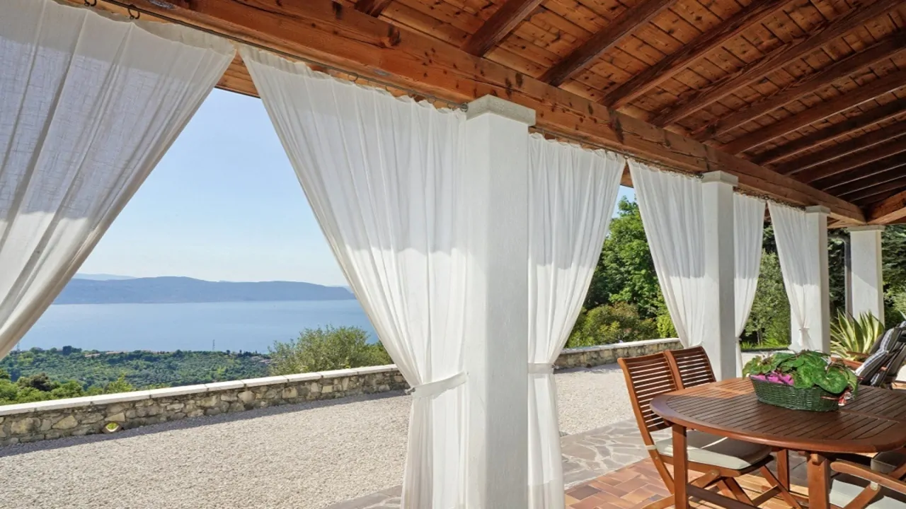 Covered terrace with white curtains and view of Lake Garda