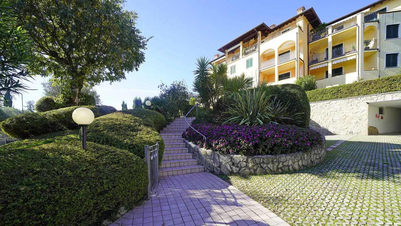 Ingresso con scale e giardino curato davanti a edificio residenziale