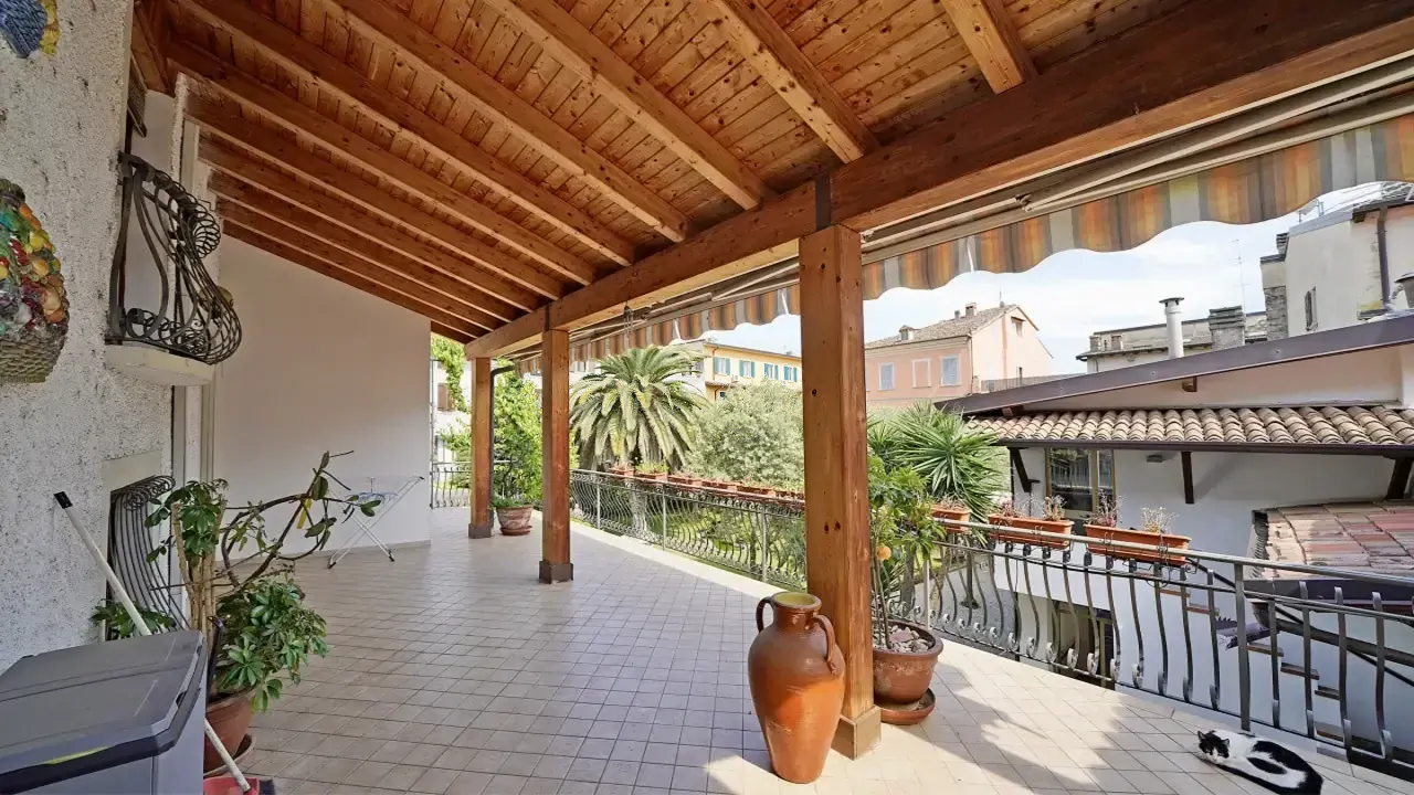 Covered terrace with wooden beams and wrought iron railing