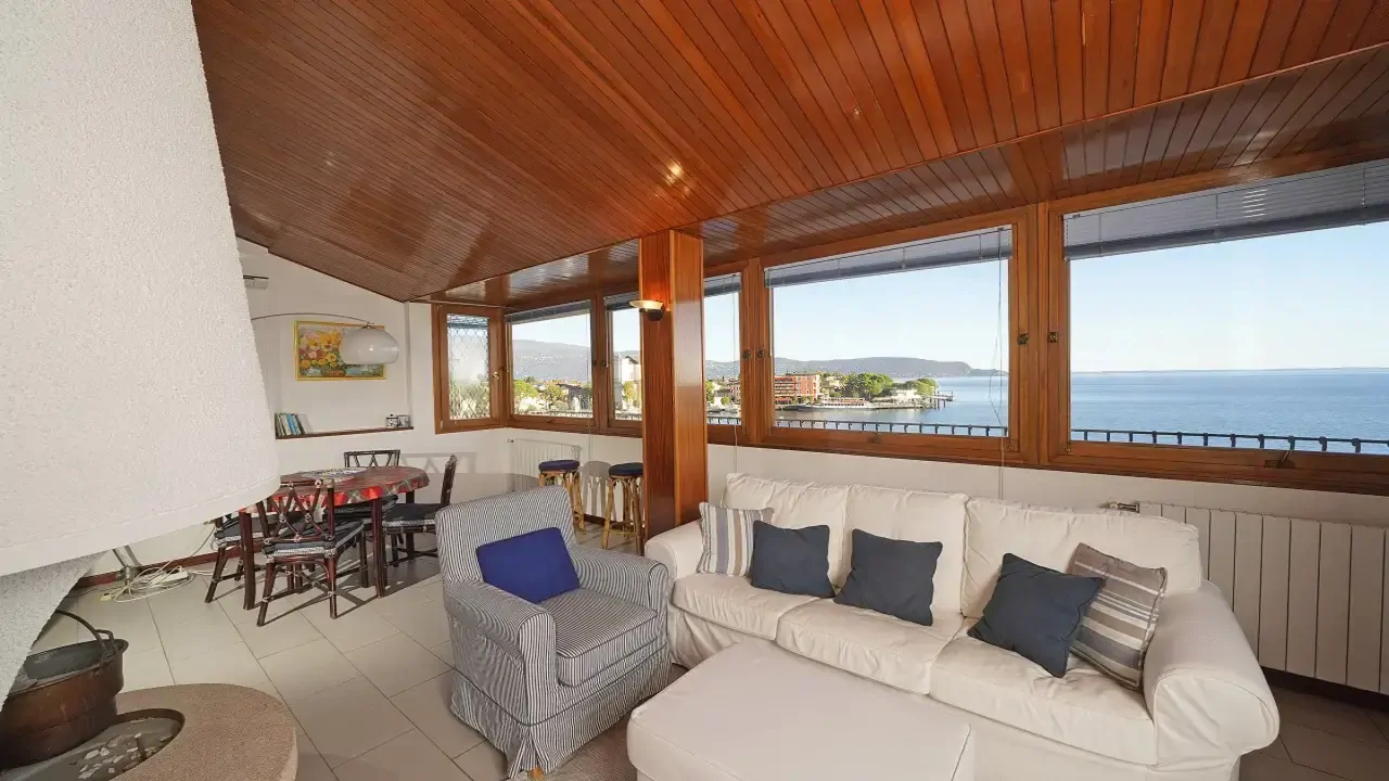 Wohnzimmer mit Sofa, Sessel und Kamin mit Blick auf die Bucht von Maderno