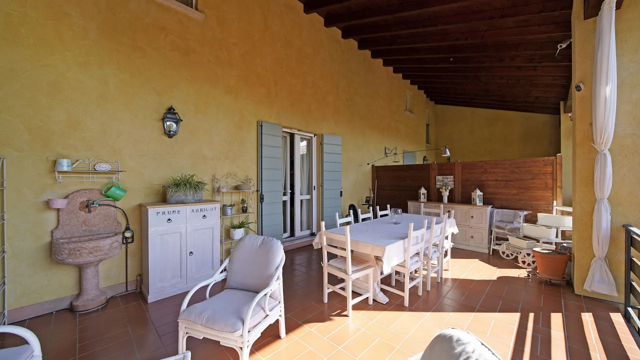 Überdachte Terrasse mit Esstisch und weißen Stühlen