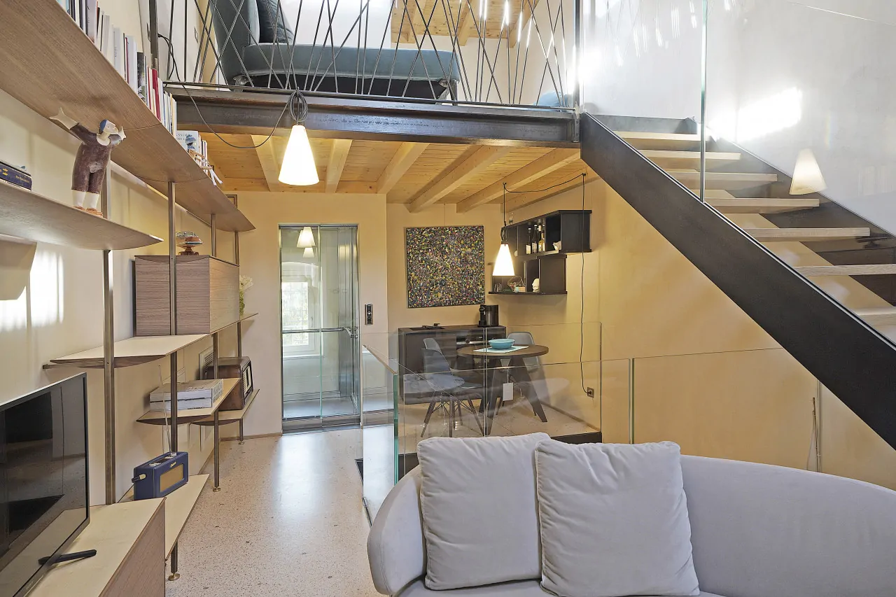 Living room with sofa, staircase and dining area in the background
