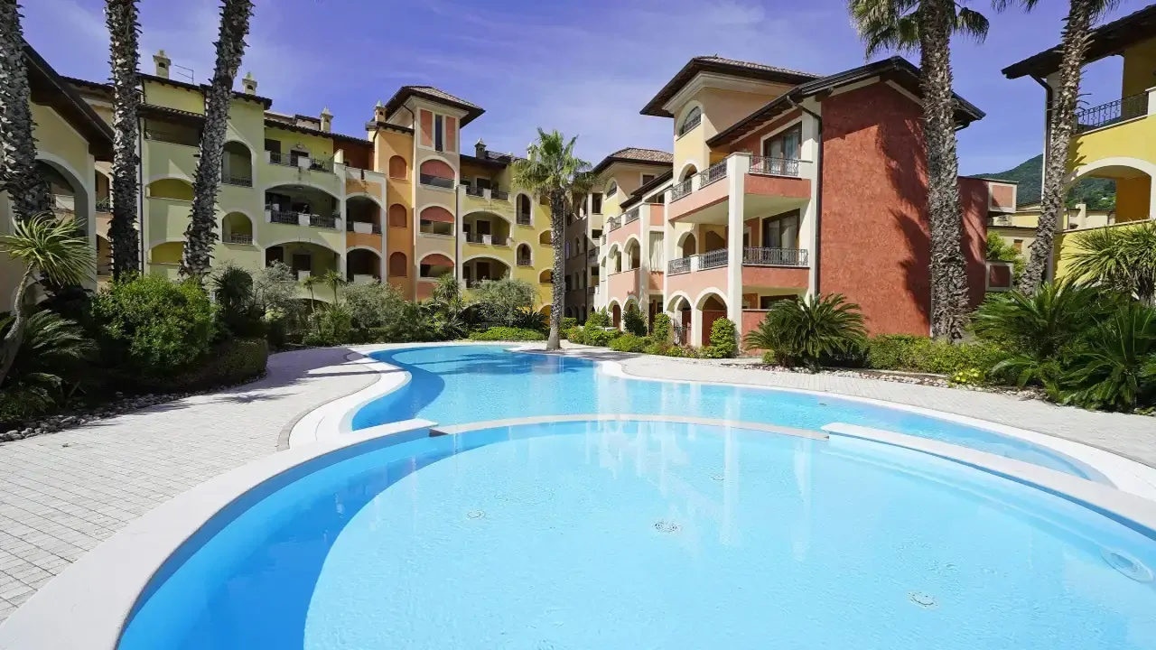 Piscina nel residence con palme e edifici colorati