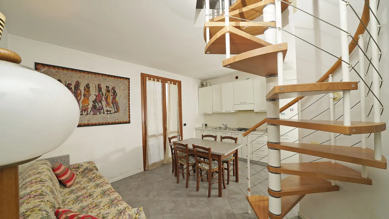 Living room with sofa, dining table and wooden metal spiral staircase