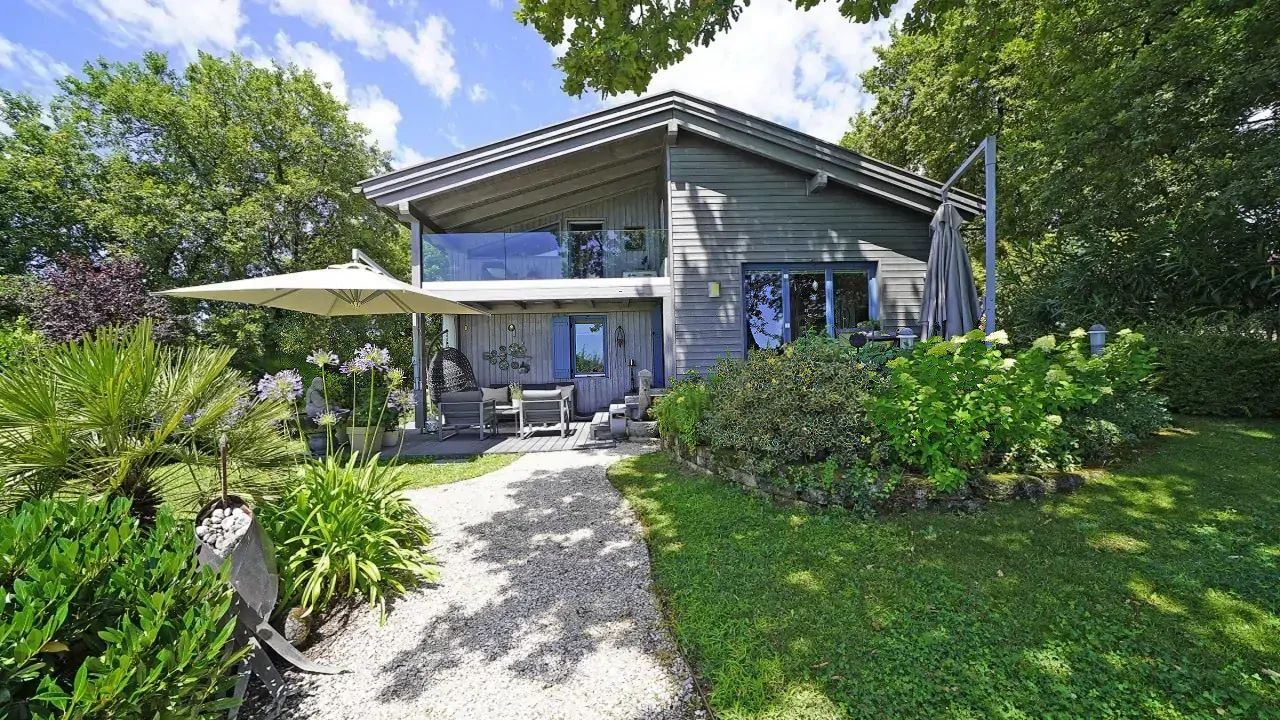 Freistehende Villa mit Garten und Terrasse mit Sonnenschirm und Liegestühlen