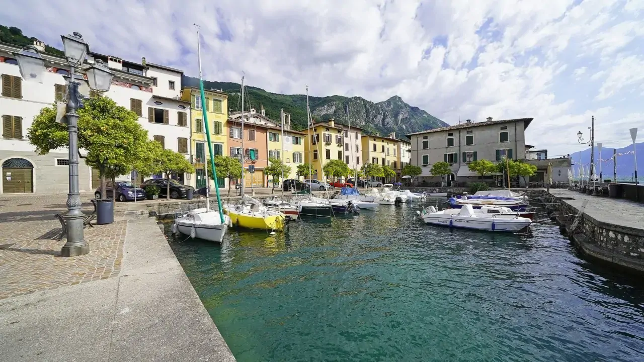 Hafen mit vertäuten Booten und bunten Häusern im Hintergrund in Gargnano