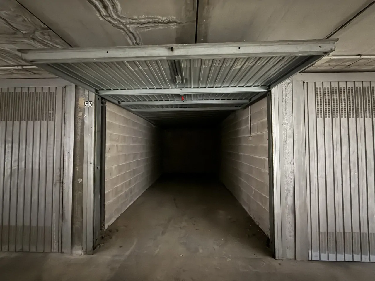 Garage mit offenem Kipptor und Betonwänden