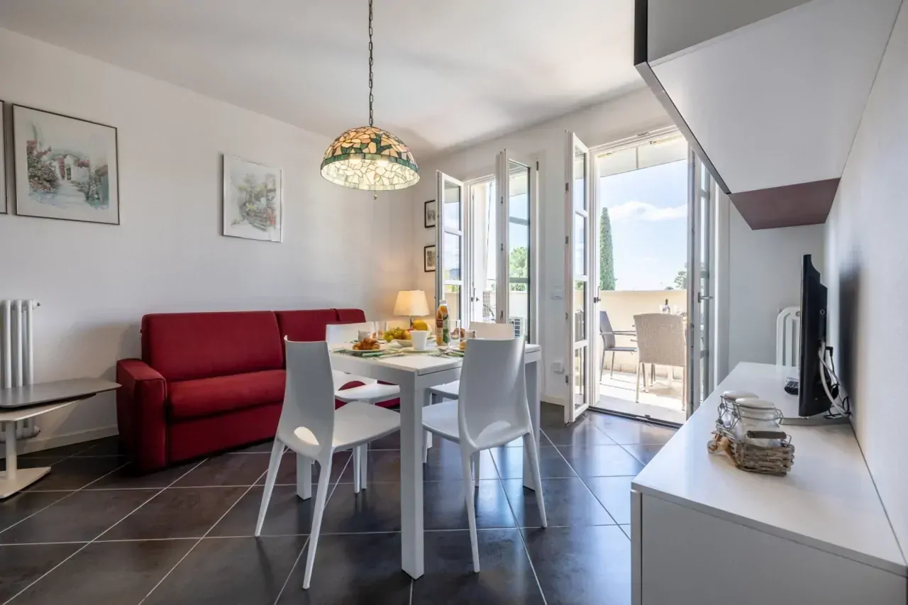 Wohnzimmer mit rotem Sofa und weißem Tisch neben offener Terrassentür