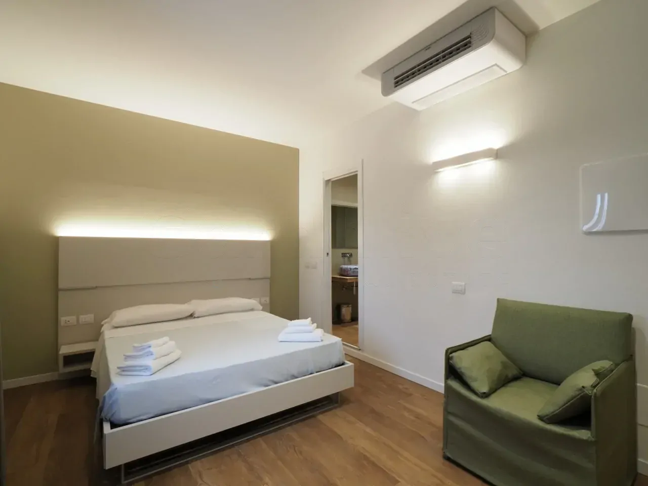 Camera con letto matrimoniale e poltrona verde