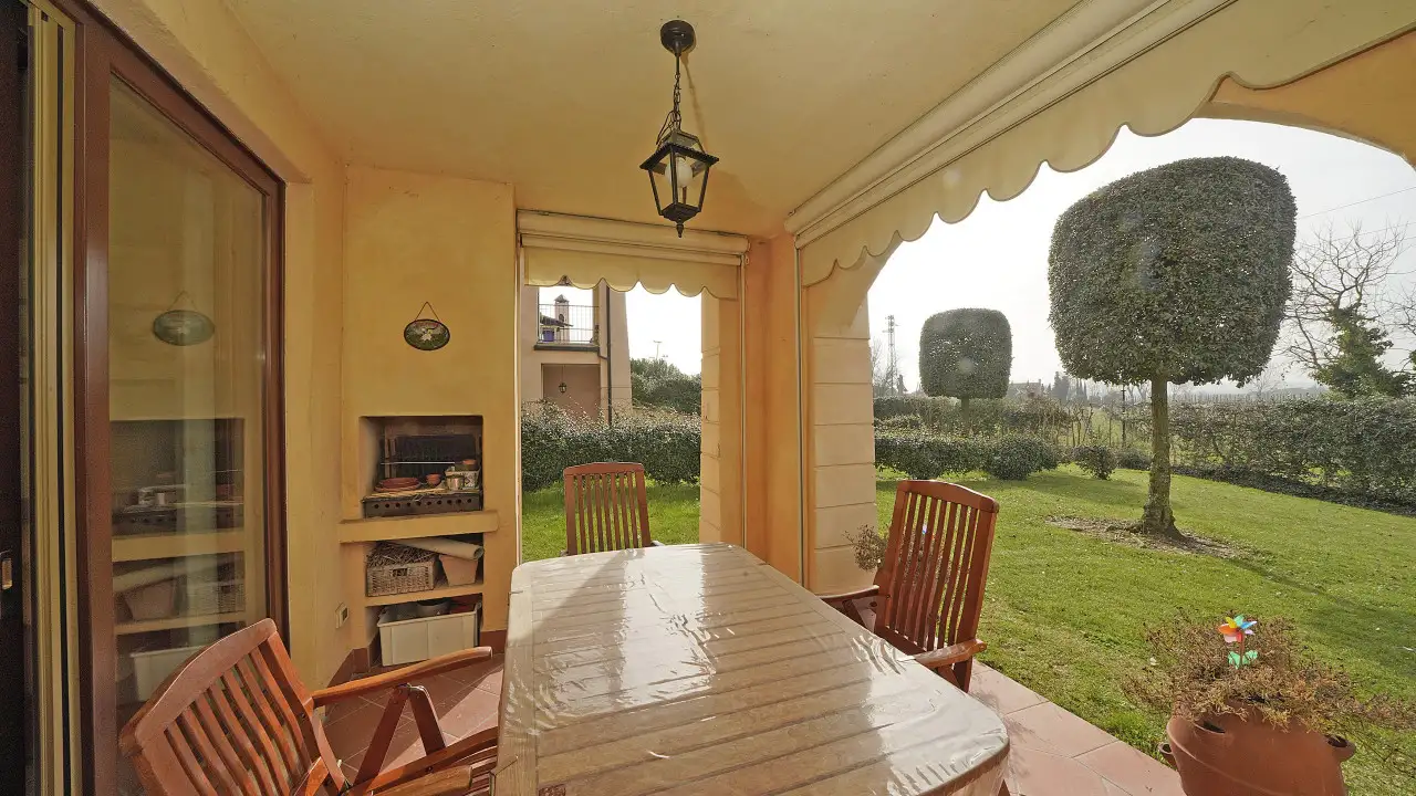 Portikus mit Holztisch und Stühlen und Blick auf den privaten Garten