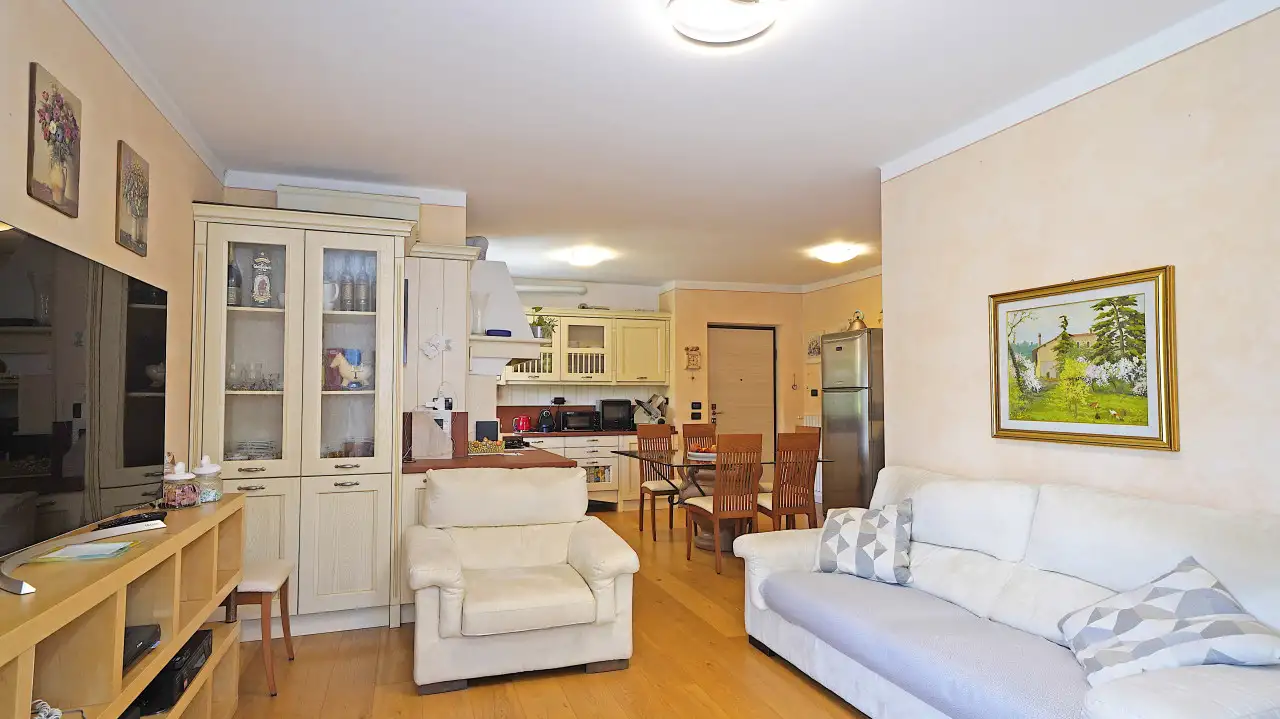 Living room with white sofas and open kitchen with dining table