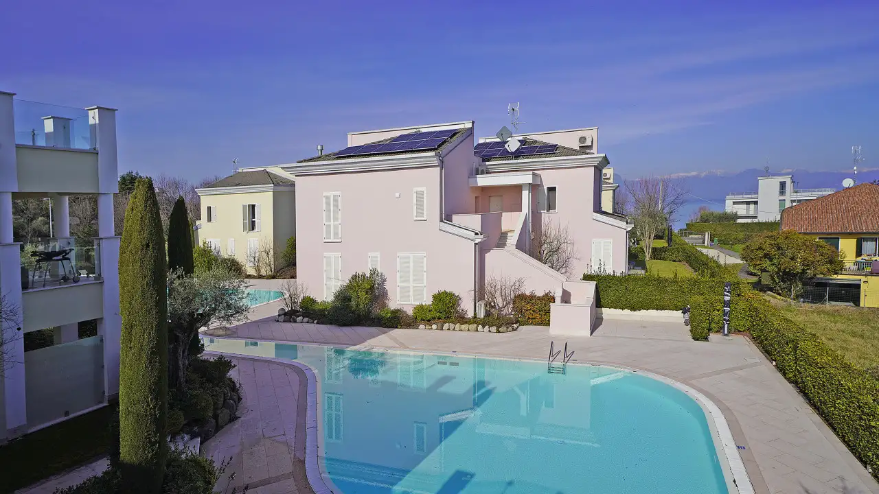 Outdoor swimming pool with villa in the background and clear sky
