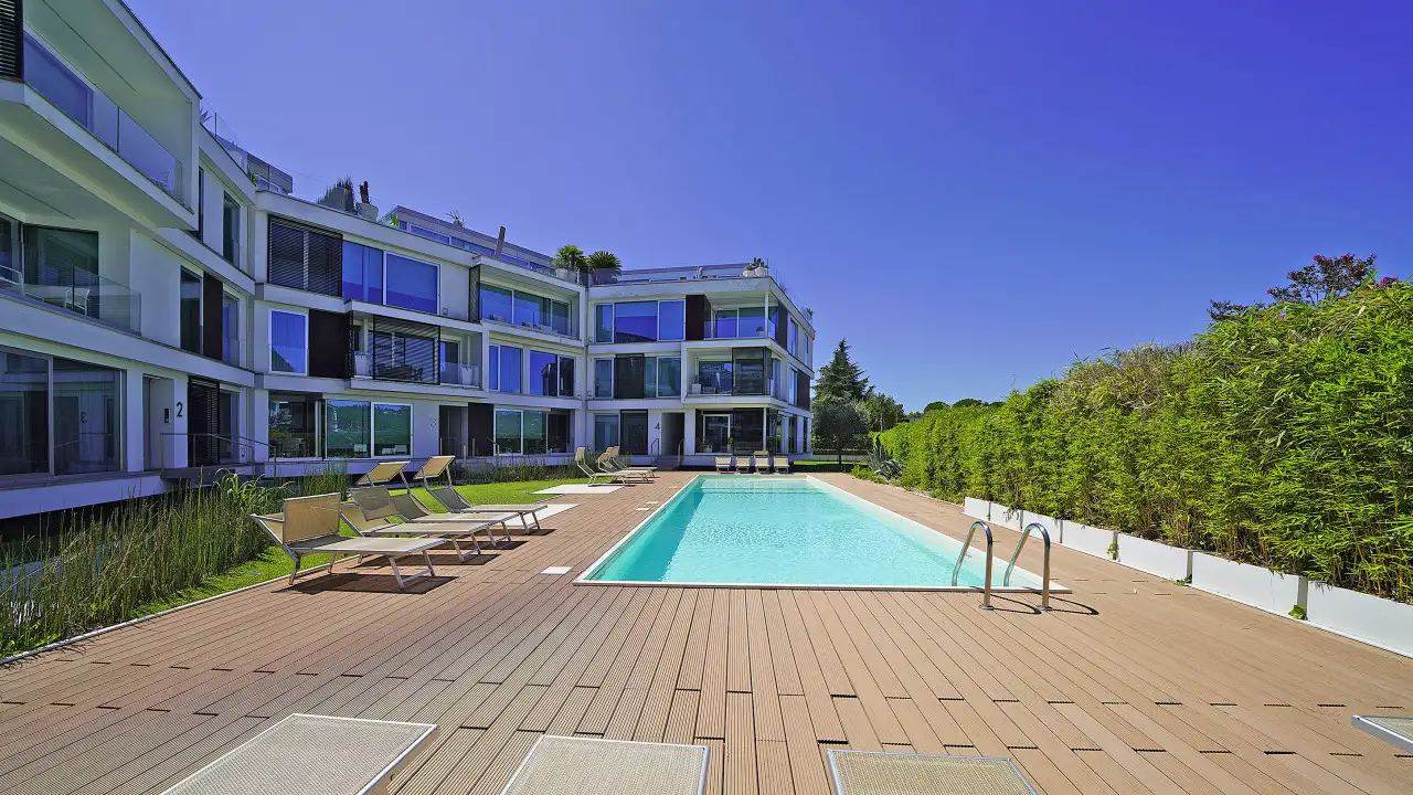 Outdoor swimming pool with sun loungers and residential building in background